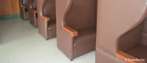Una hilera de sillones marrones de cuero con reposabrazos de madera en una habitación con suelo de baldosas y paneles de madera.