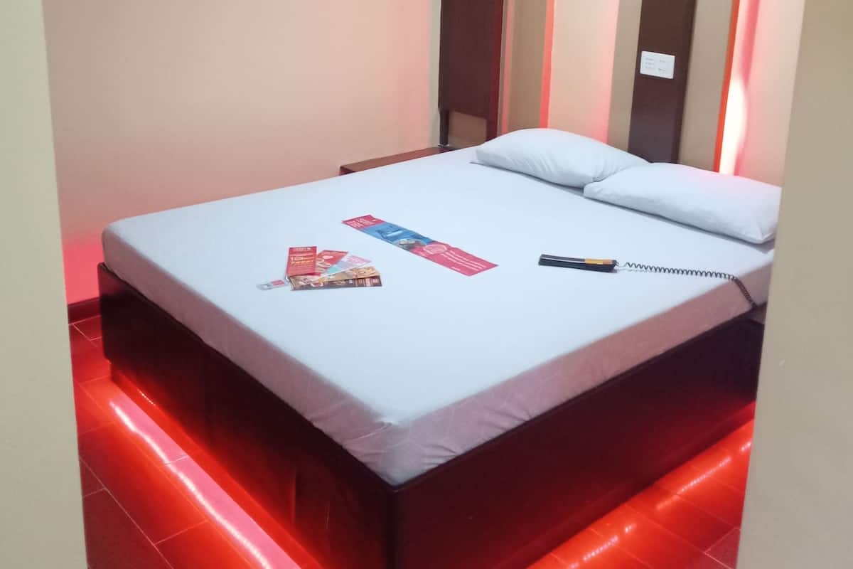 A neatly made bed with a white mattress and pillows, a red and white striped wall, and a red neon light strip along the floor.