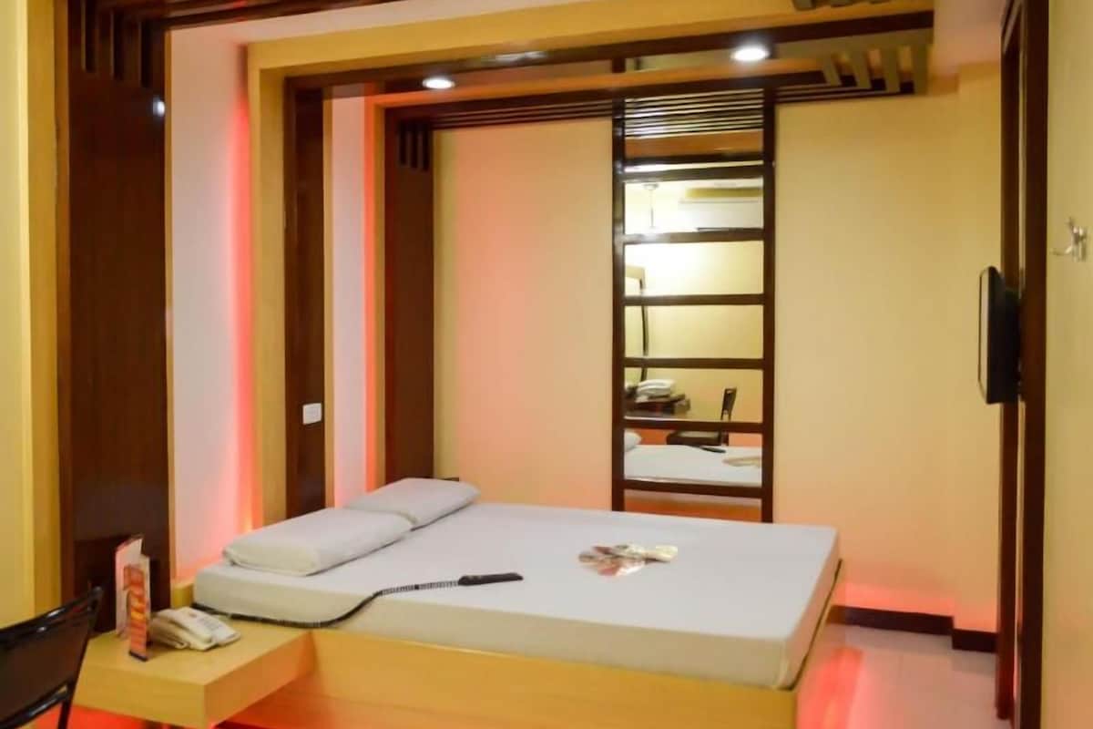 A bedroom with a bed, bedside table, and a built-in shelving unit.