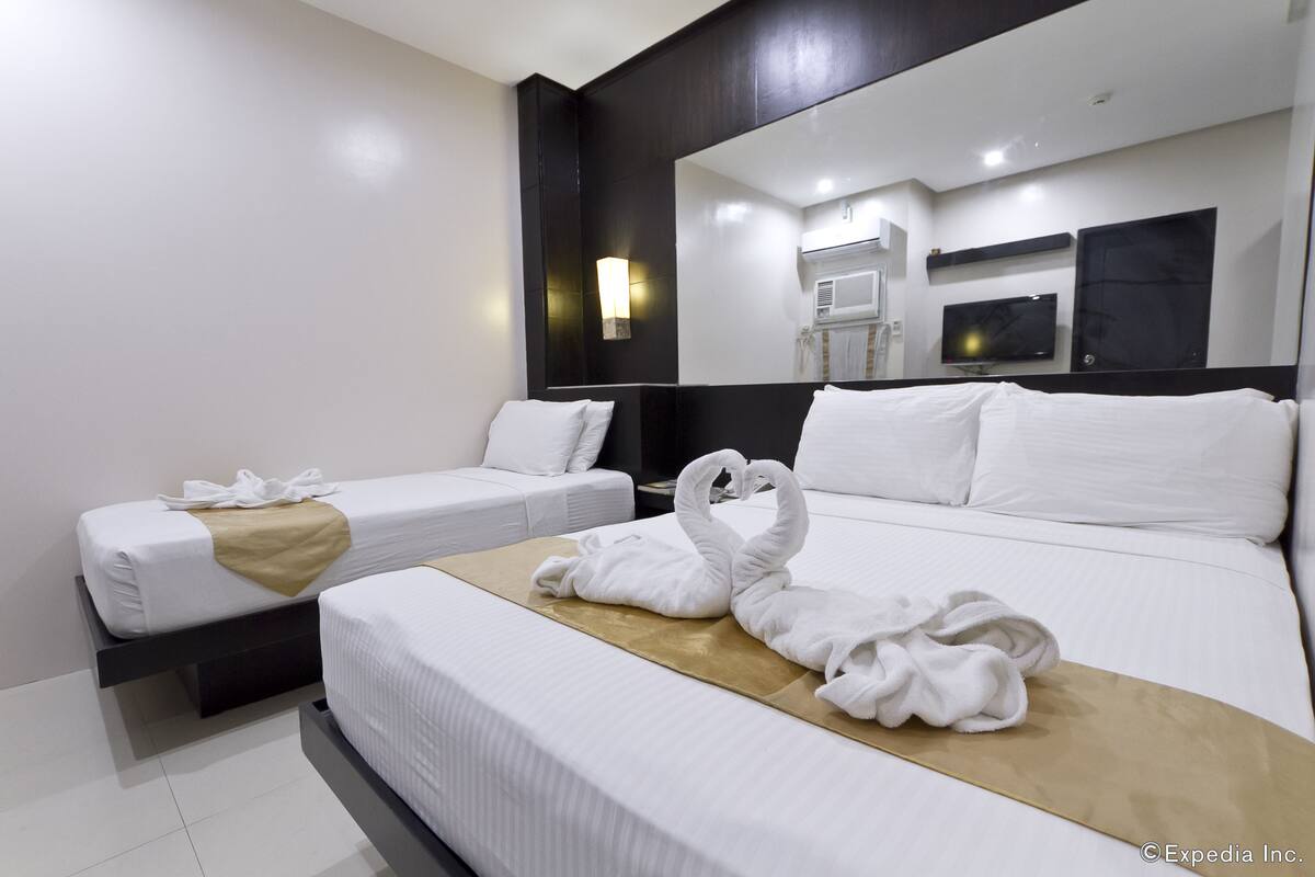 A hotel room with two beds, a TV, and a mirror.