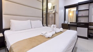 Quarto de hotel com uma cama grande, uma mesa, uma cadeira e um espelho.