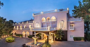 A large, multi-story building with a central courtyard, arched windows, and a fountain. - Club Mahindra Emerald Palms, Goa (Varca)