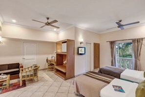 A hotel room with two beds, a desk, a chair, a TV, and a balcony with curtains.