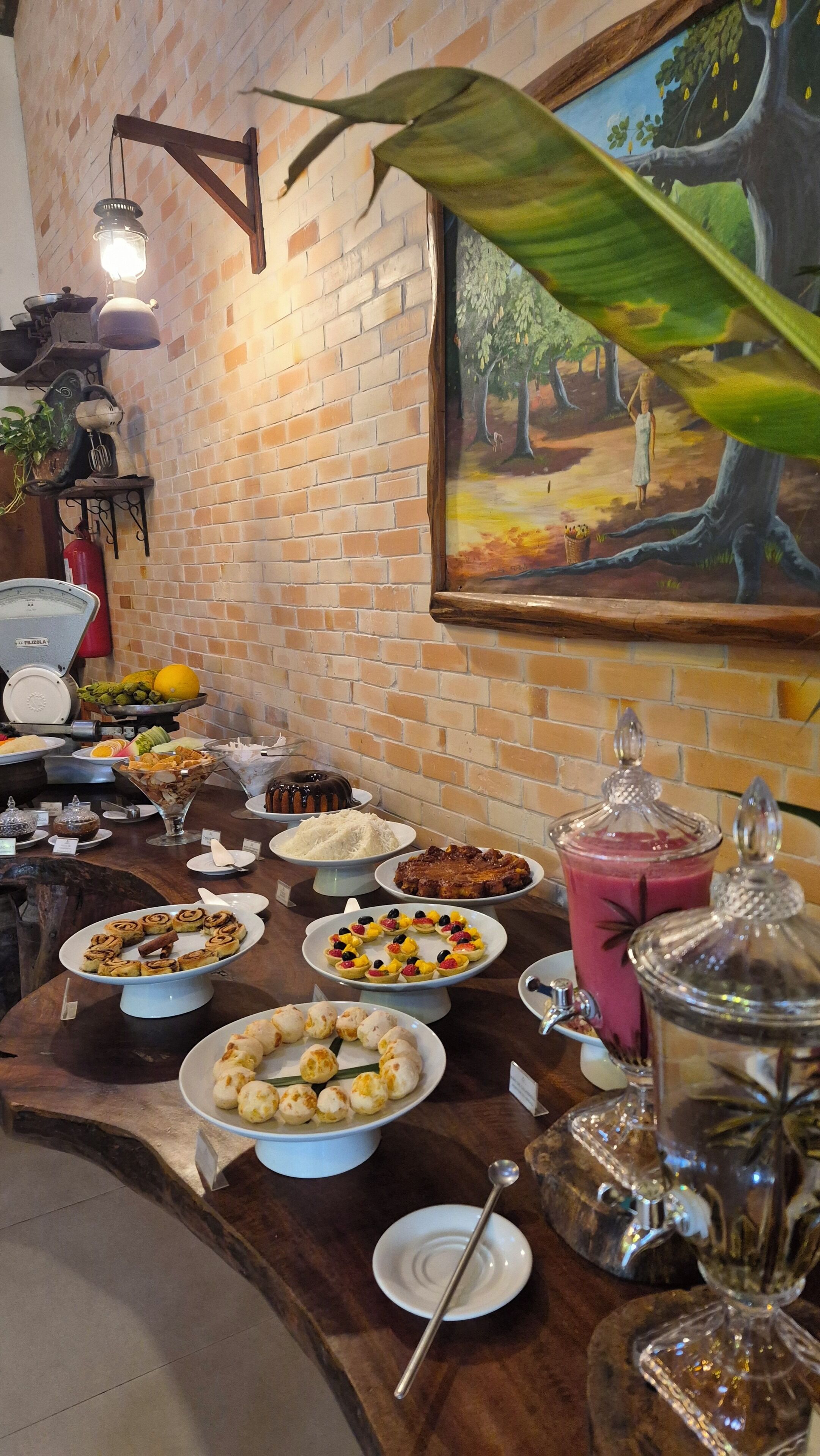 A buffet with various dishes, a brick wall, and a painting of a tree.