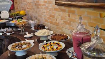 A buffet with various dishes, a brick wall, and a painting of a tree.