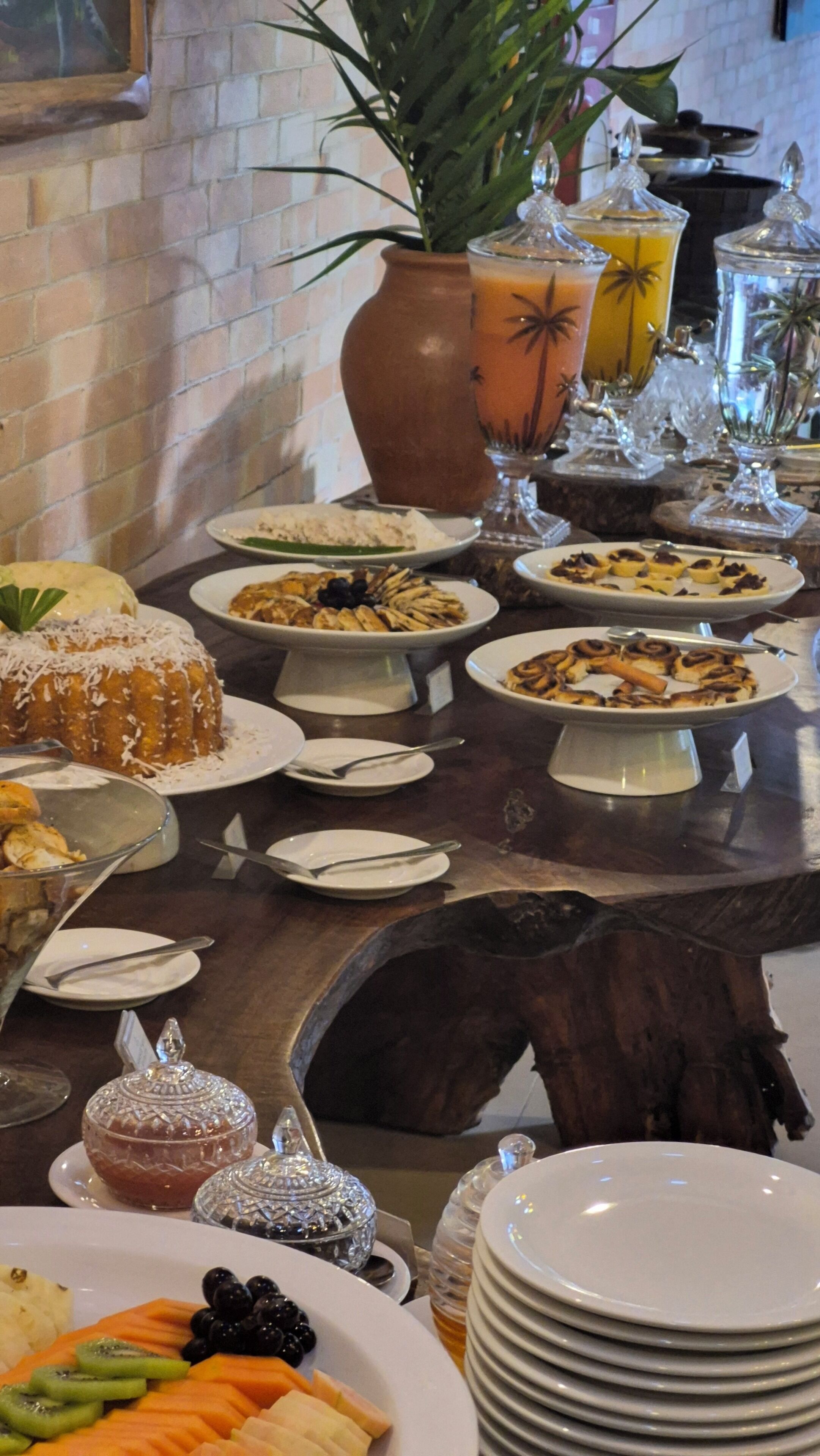 A buffet table with various dishes, including a cake, fruit, and a drink.