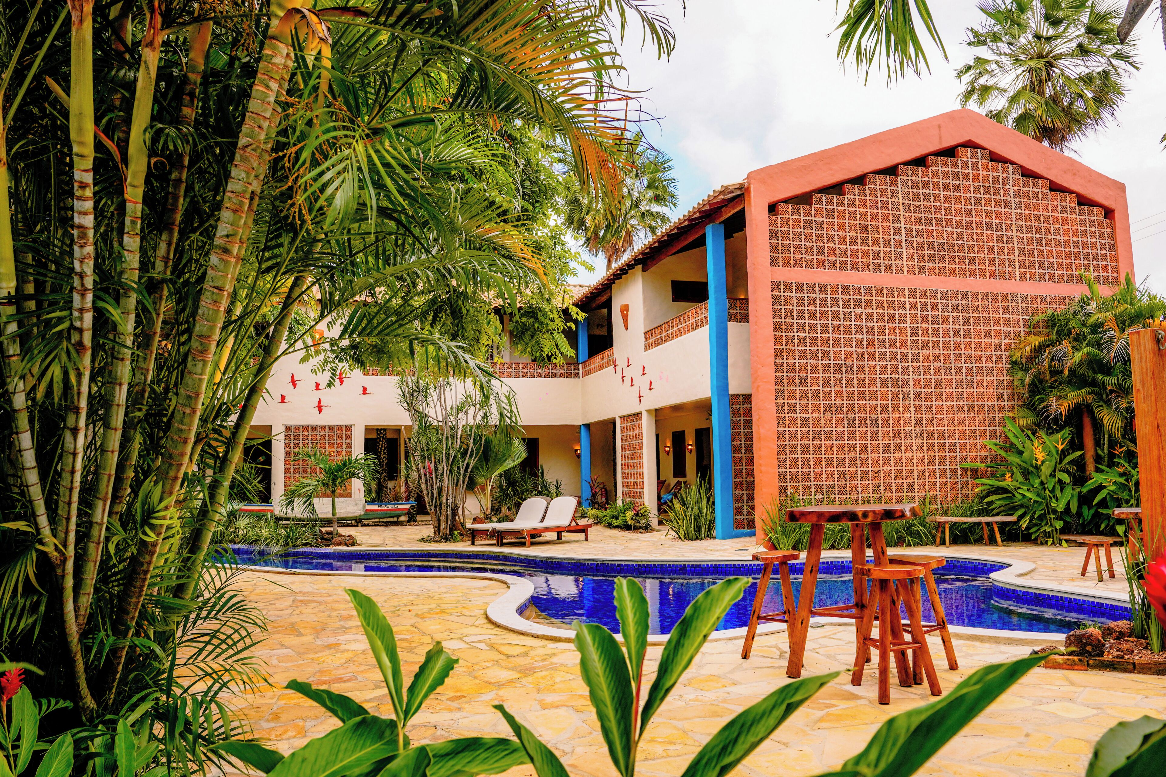 A resort with a swimming pool, lounge chairs, and tropical plants.