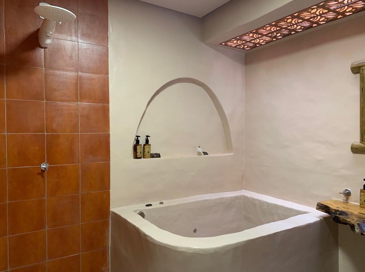 Un baño con bañera, ducha y un estante con artículos de aseo.