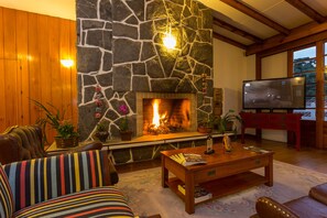 Una sala de estar acogedora con chimenea de piedra, mobiliario de madera y televisor.