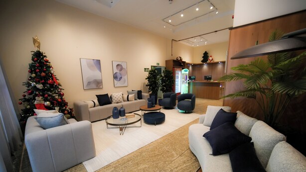 Una sala de estar moderna con un árbol de Navidad, sofás y un mostrador de recepción.
