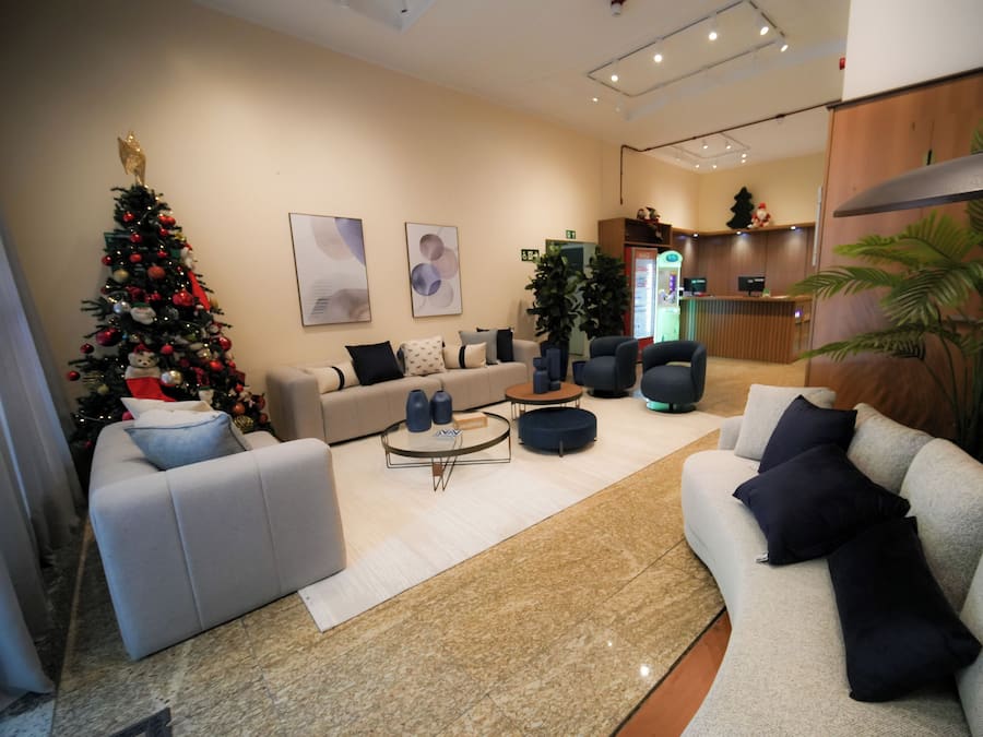 A modern living room with a Christmas tree, sofas, and a reception desk.