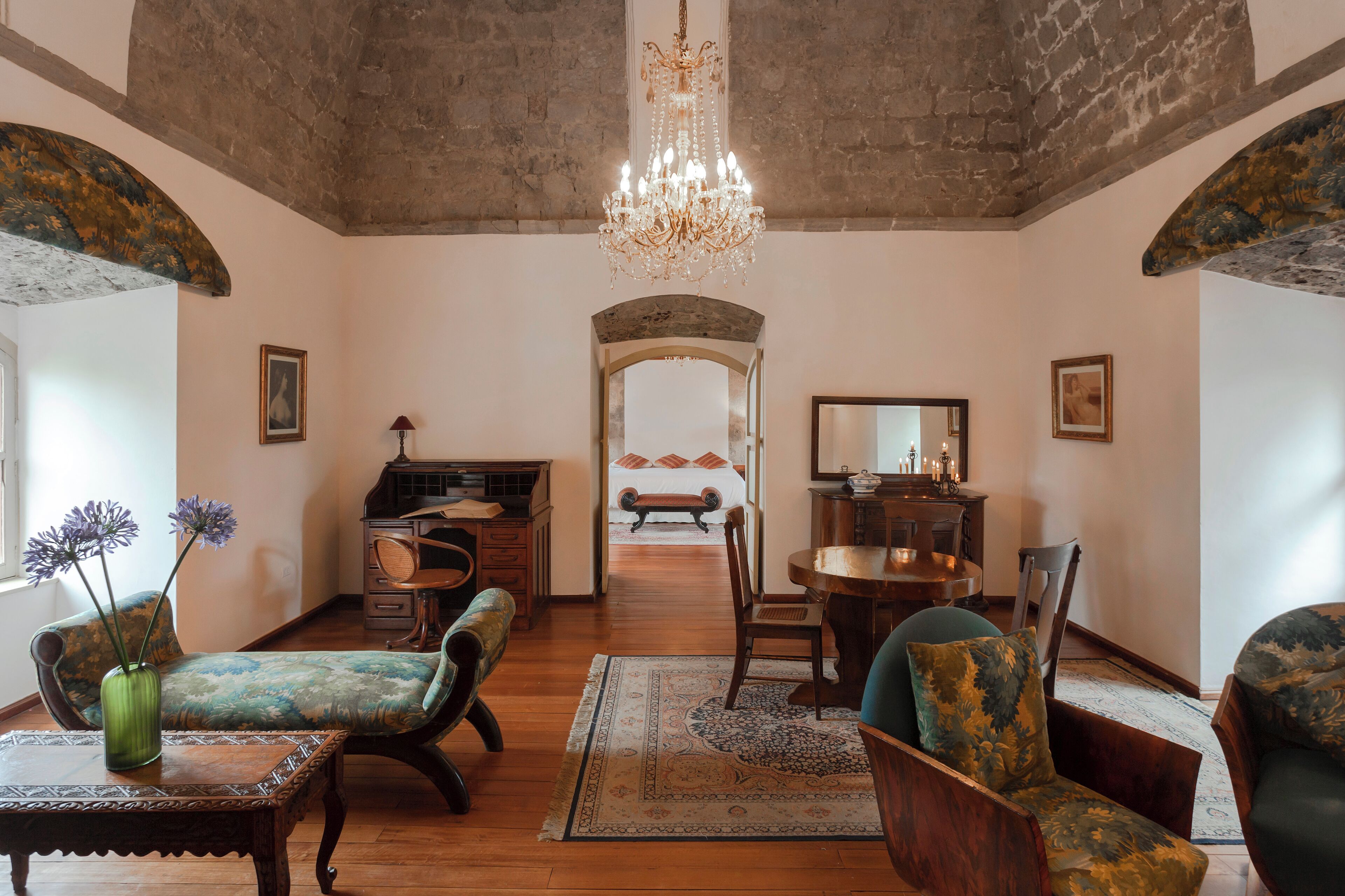 A room with a chandelier, wooden furniture, and a large mirror.