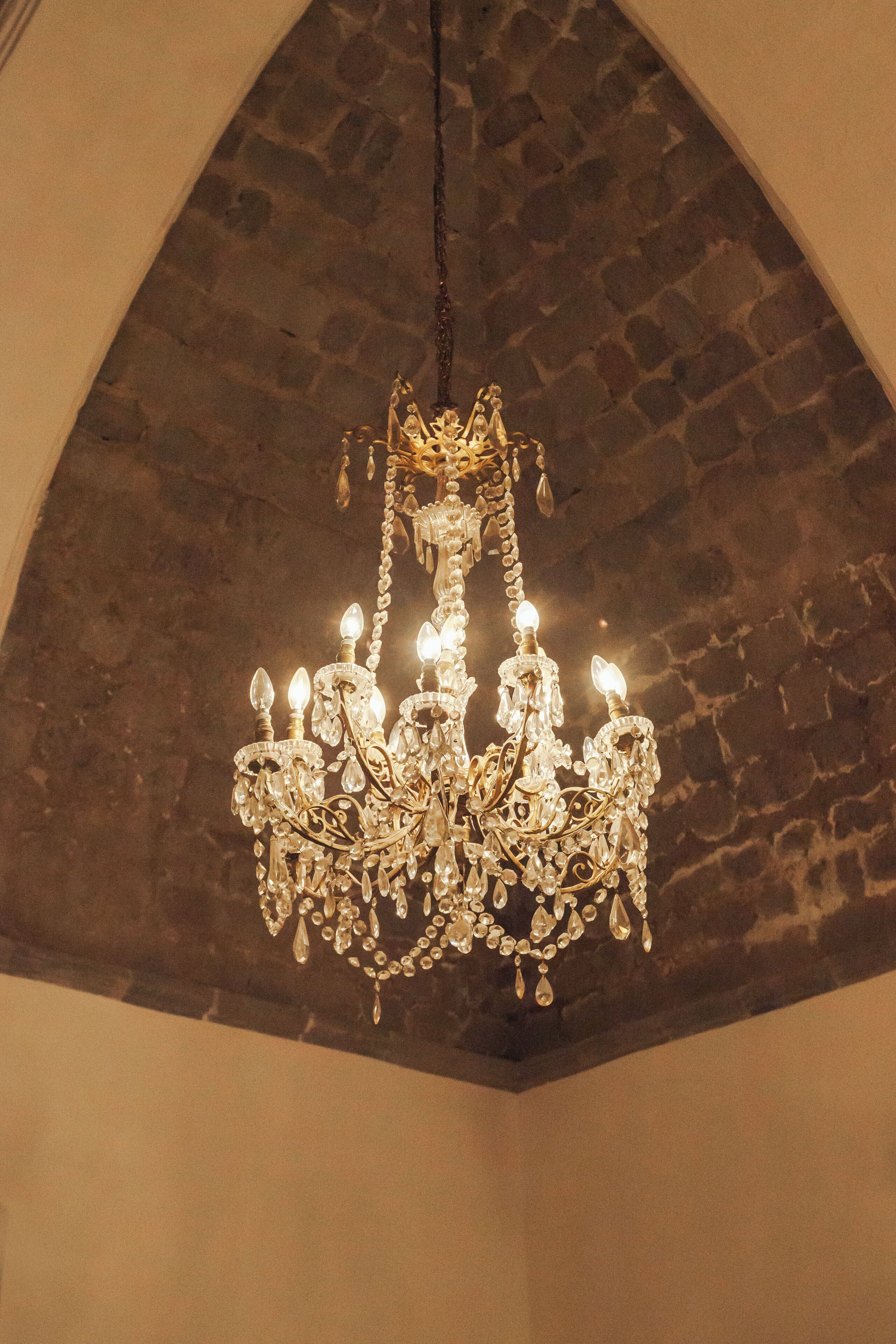 Un lustre à plusieurs lampes suspendu à un plafond en pierre.