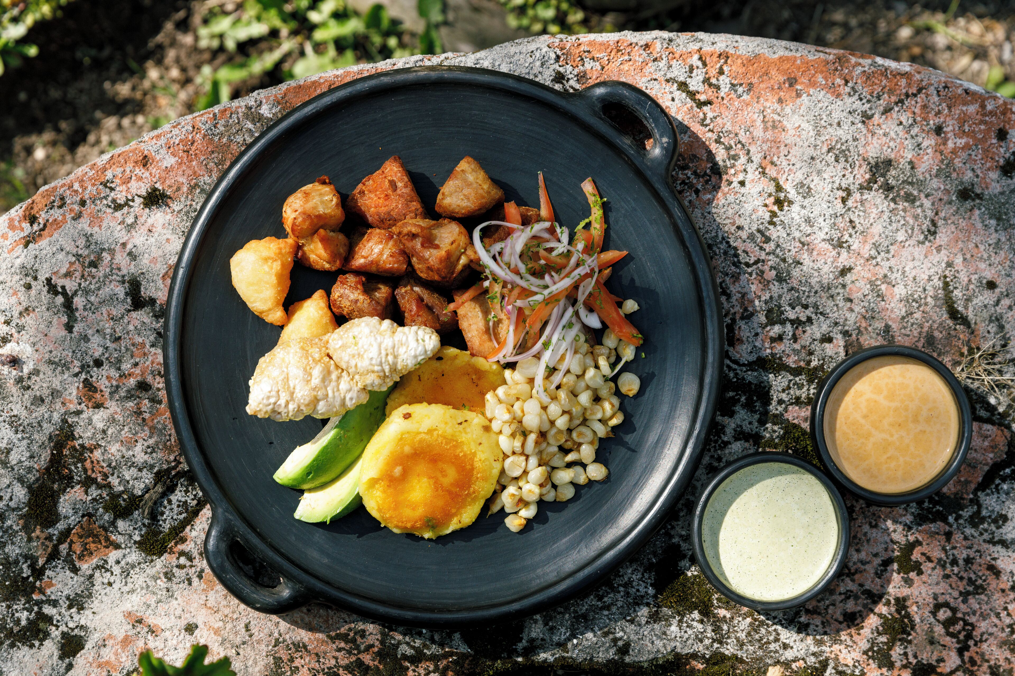A black plate with various food items on a stone surface.