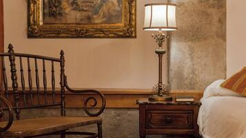 A bedroom with a wooden bed, a nightstand with a lamp, a chair, and a painting on the wall.