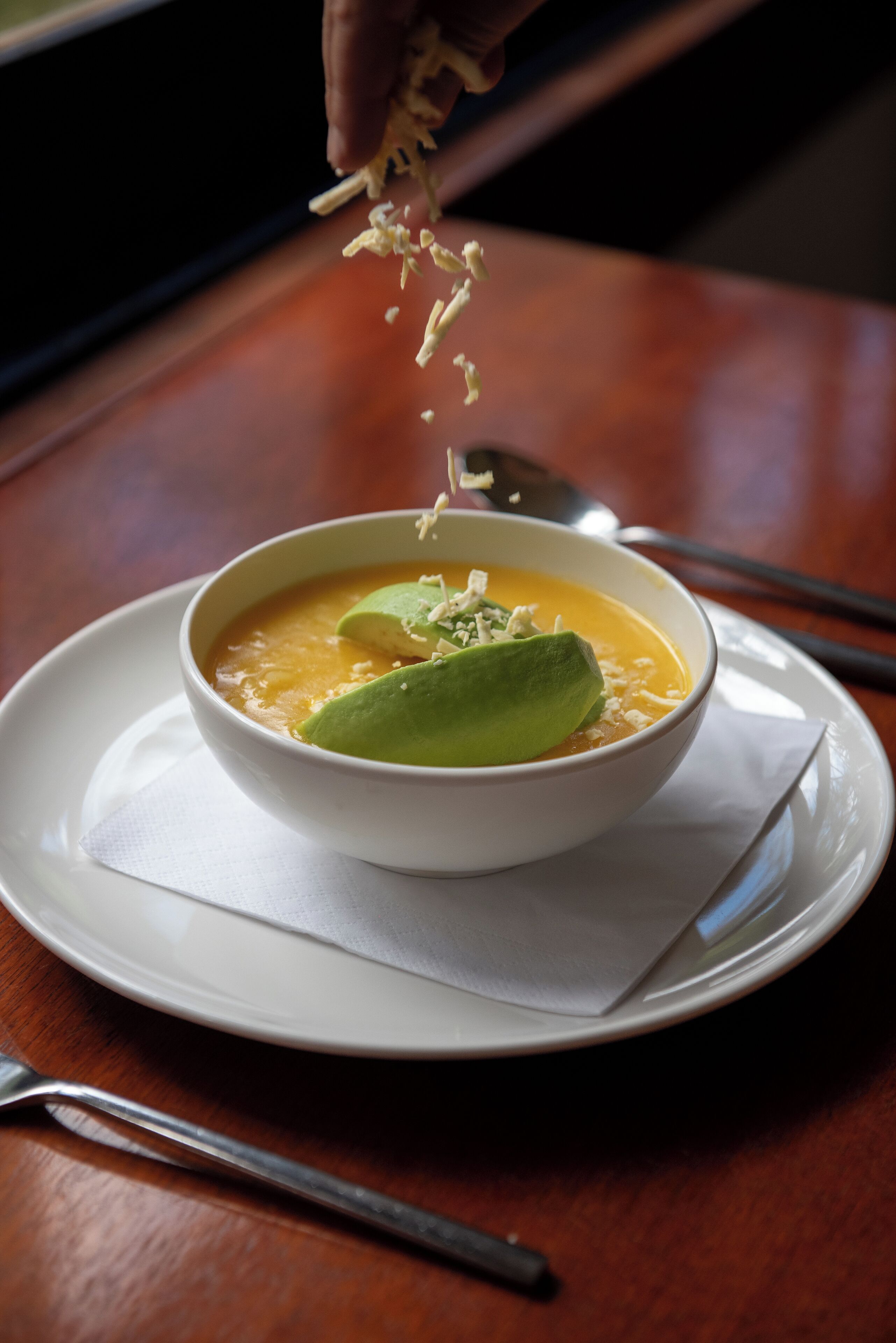 A bowl of soup with a green garnish on a white plate.