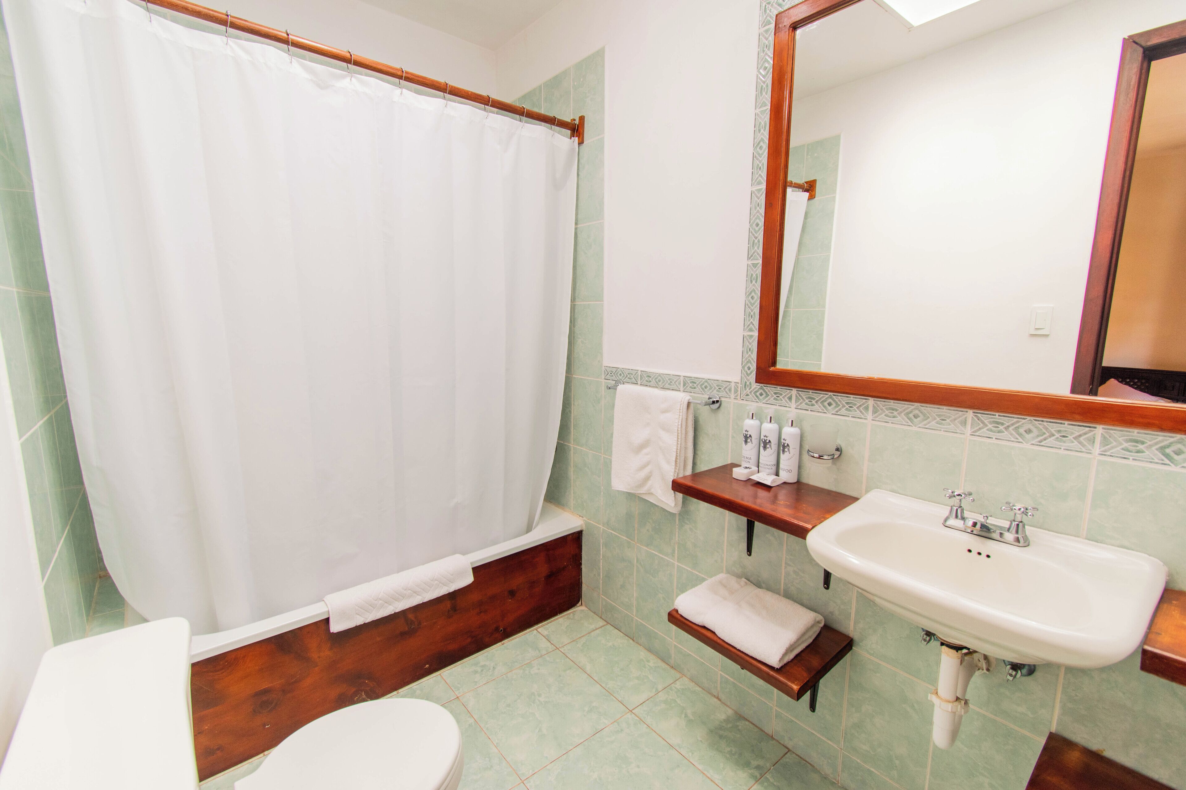 A bathroom with a bathtub, toilet, sink, and mirror.