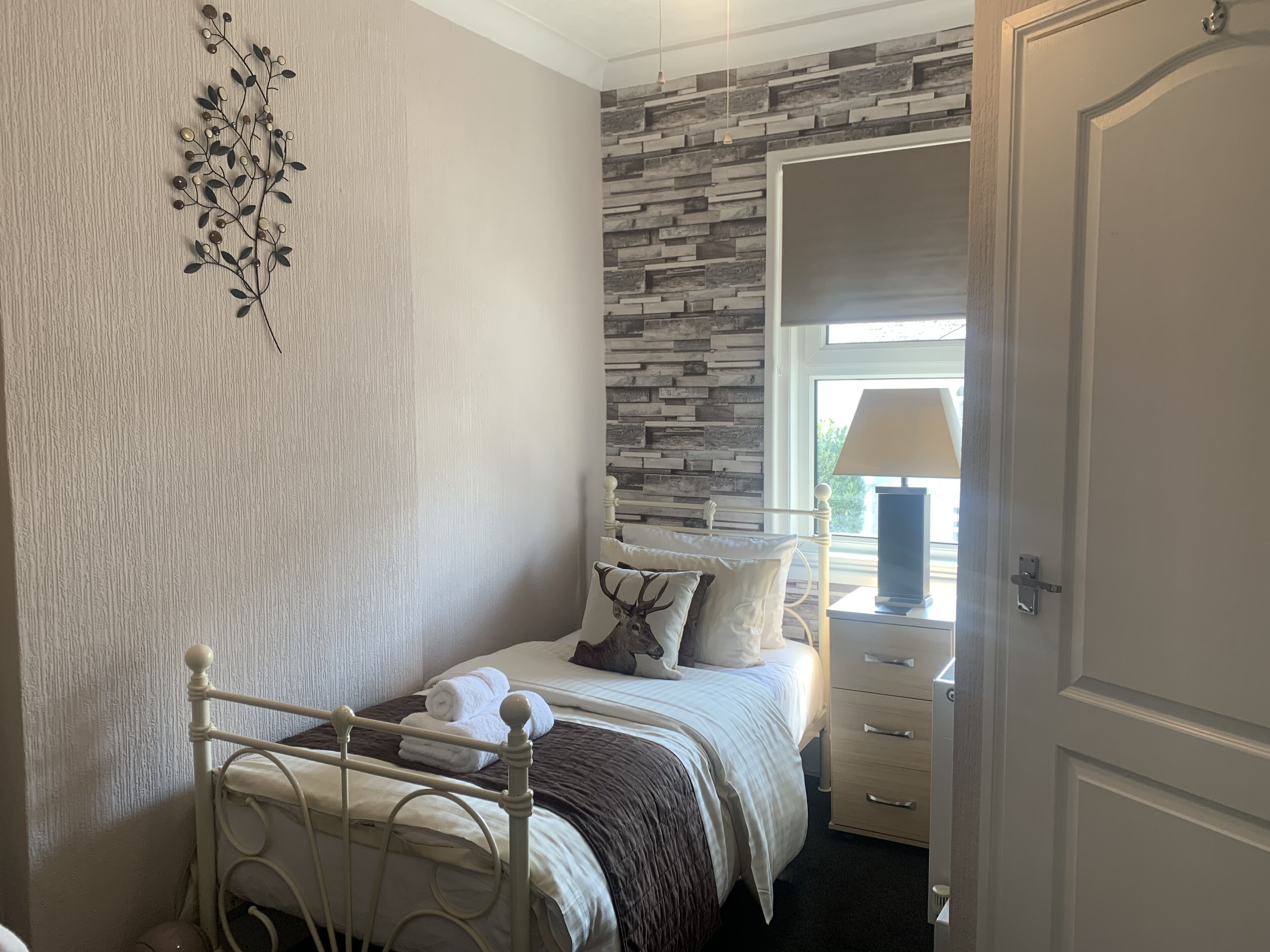 A bedroom with a bed, a nightstand, a lamp, and a decorative wall piece.