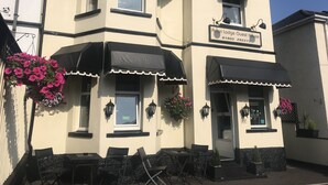 A two-story building with a sign reading "Arran Lodge Guest House" and a number "01803 292273".