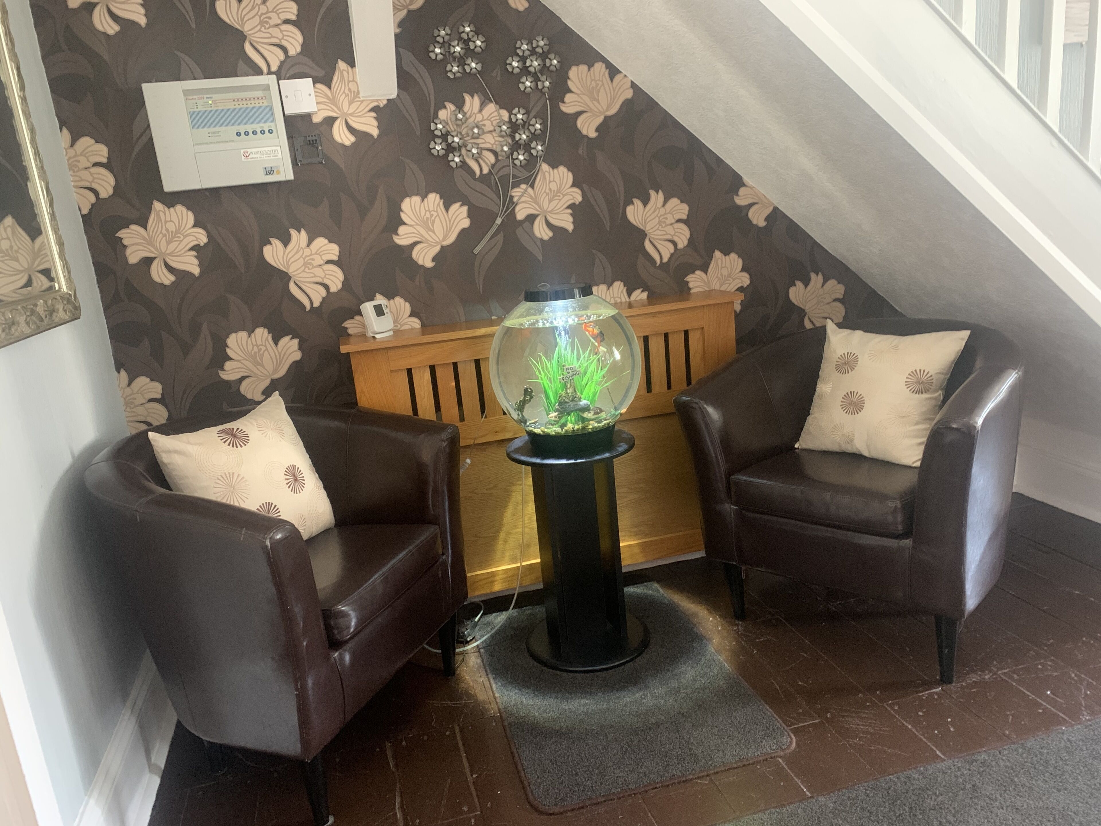A cozy room with two leather armchairs, a wooden bench, and a fish tank.