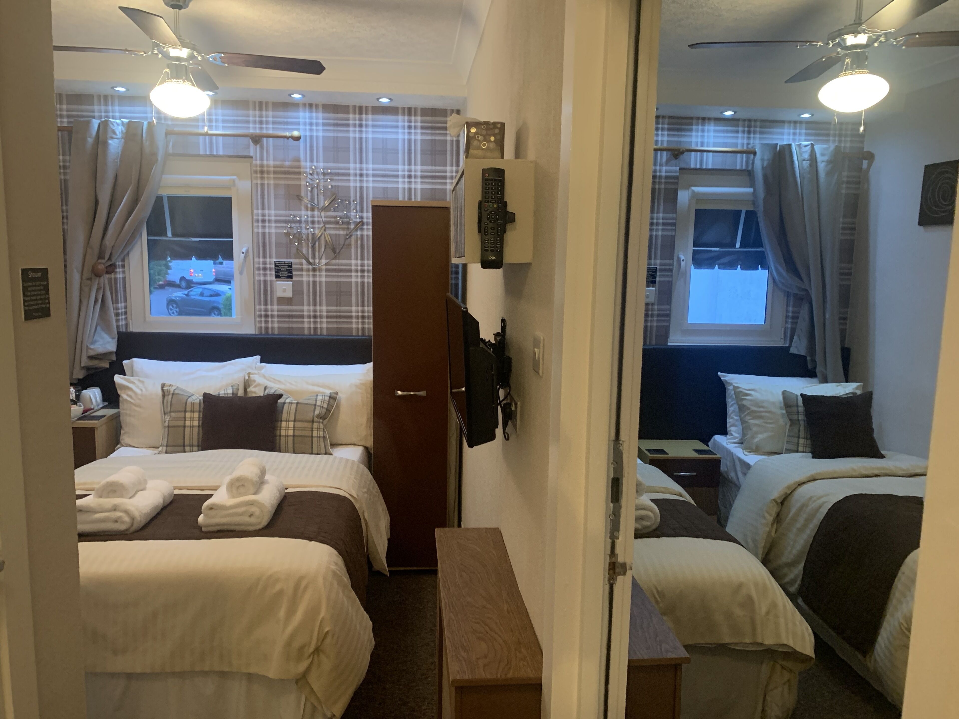 Una habitación de hotel con dos camas, un armario, un escritorio y un espejo.