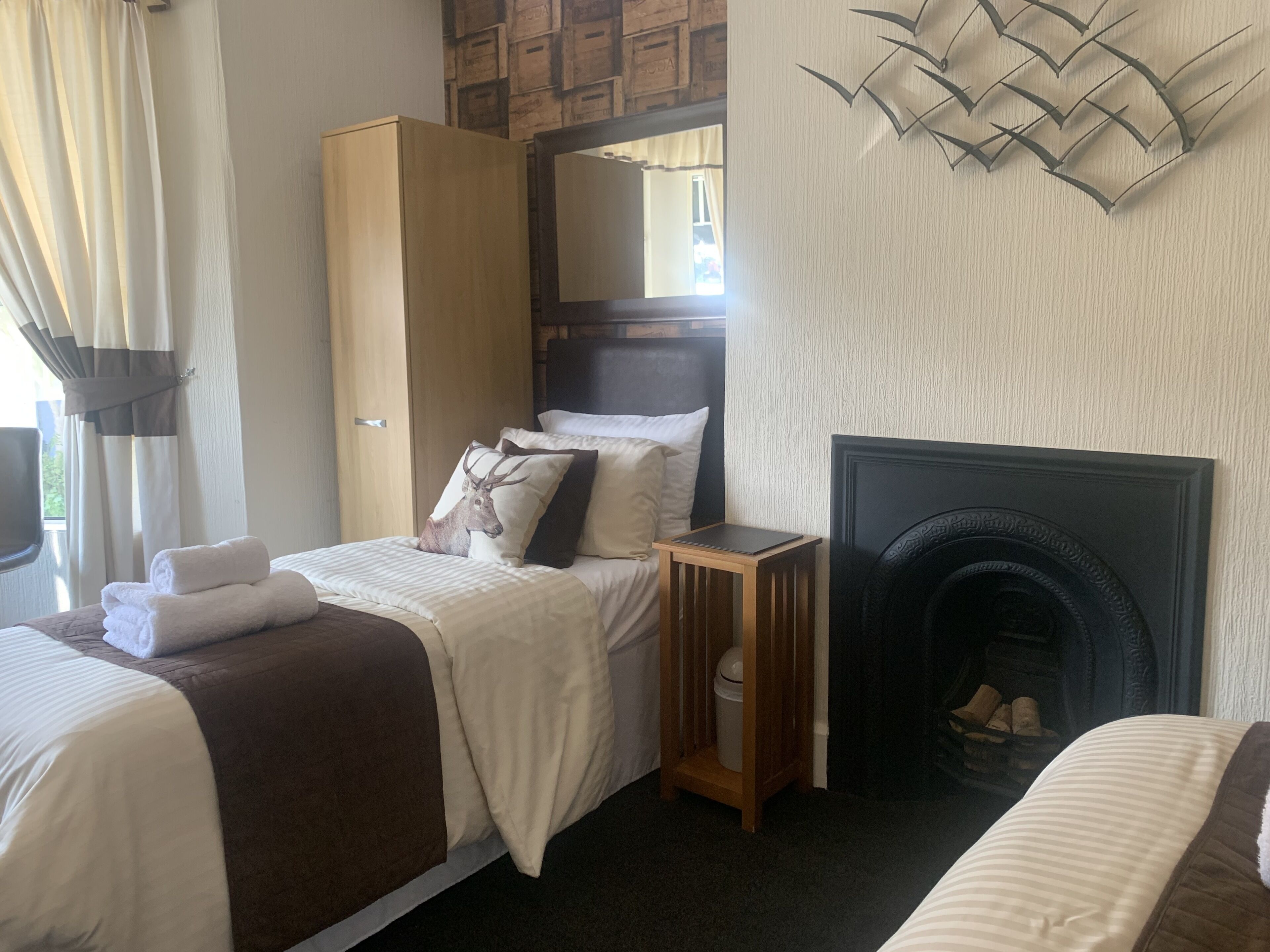 Habitación de hotel con cama, armario, mesita de noche, chimenea y un adorno en la pared.