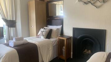 Habitación de hotel con cama, armario, mesita de noche, chimenea y un adorno en la pared.