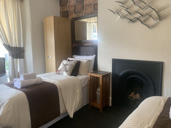 Habitación de hotel con cama, armario, mesita de noche, chimenea y un adorno en la pared.