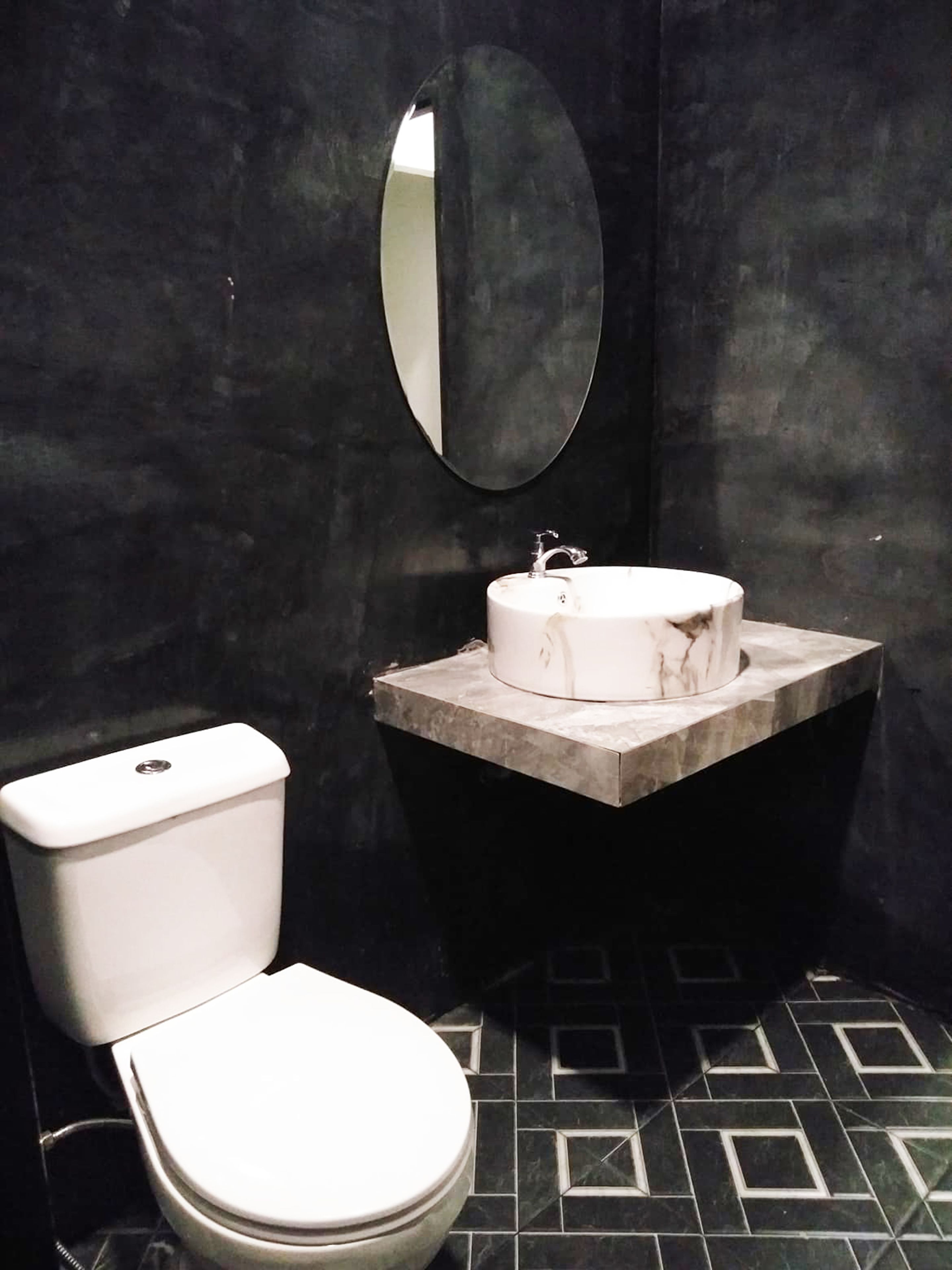 Ein Badezimmer mit Toilette, einem Waschbecken mit Marmorplatte und einem Spiegel.