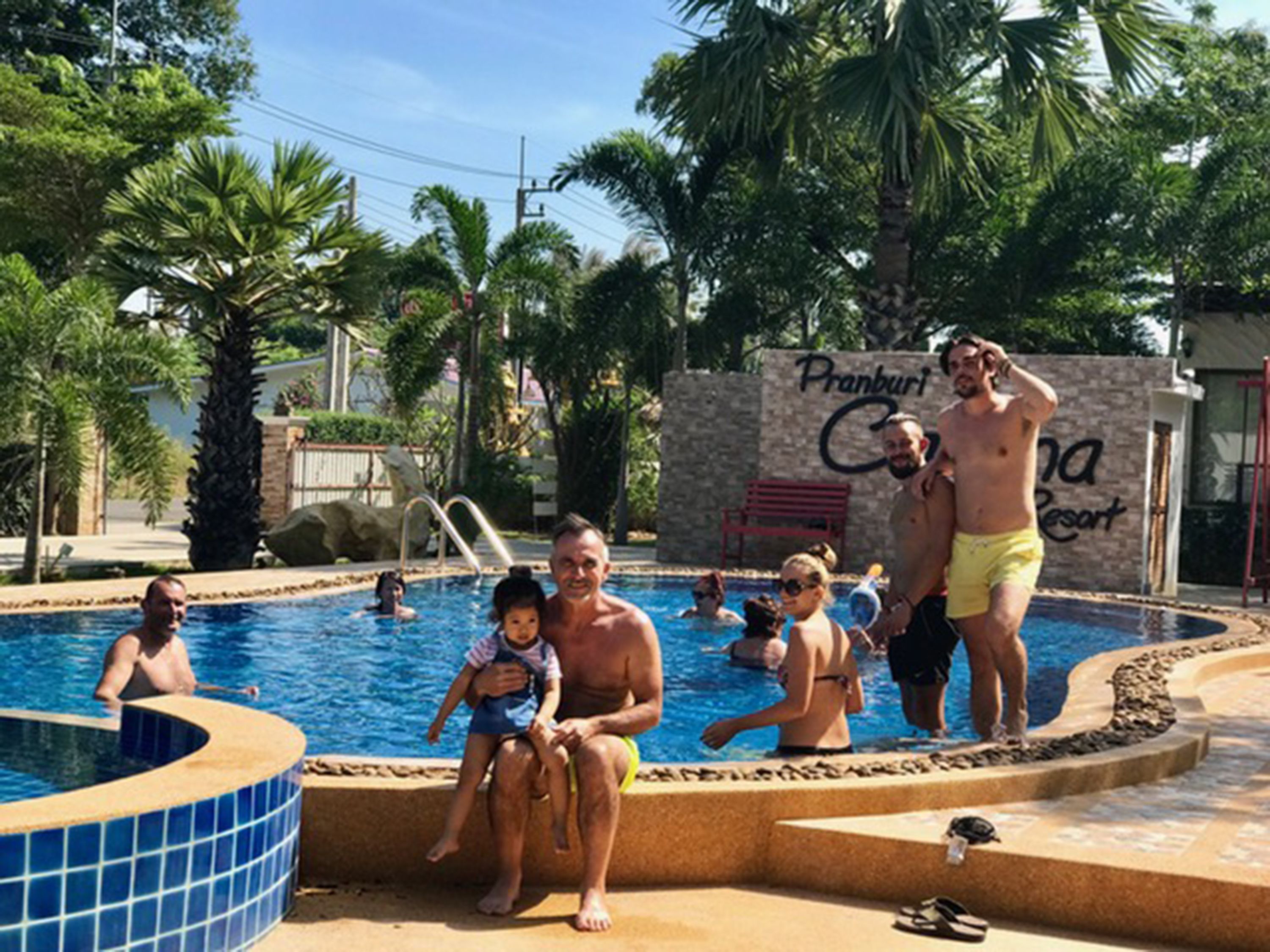 A swimming pool area with a stone wall labeled "Pranburi Resort."
