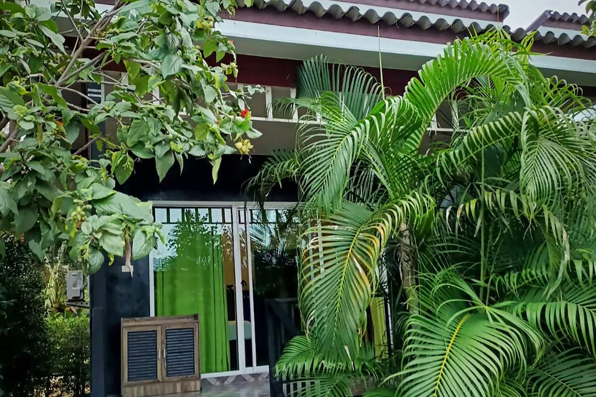 Um edifício com entrada coberta de azulejos, cercado por vegetação exuberante e uma palmeira.