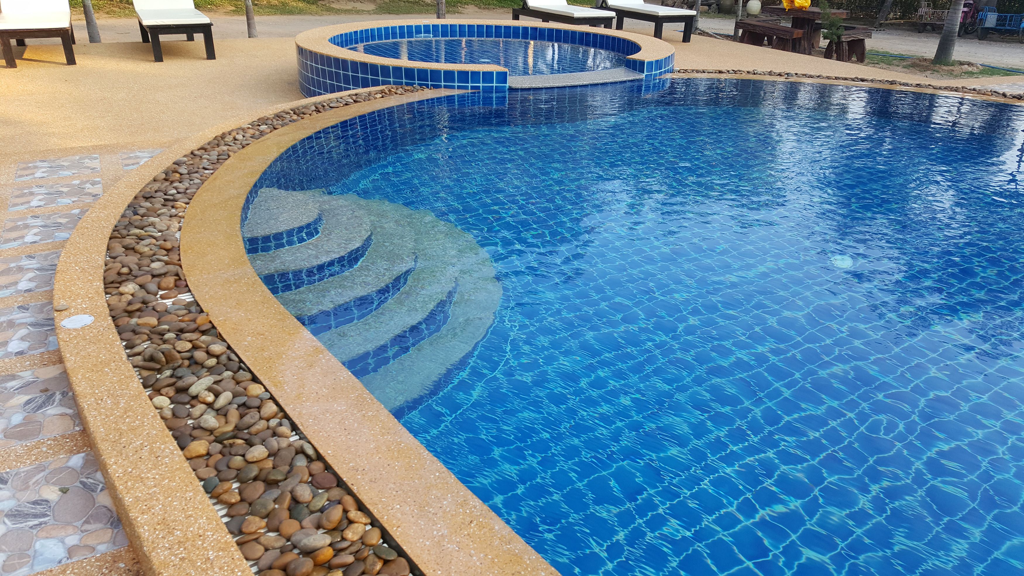 A swimming pool with a tiled edge and a pebble border.