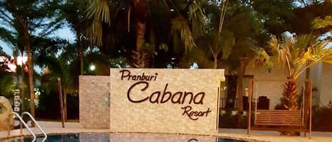 Señal del Pranburi Cabana Resort con una piscina al frente.