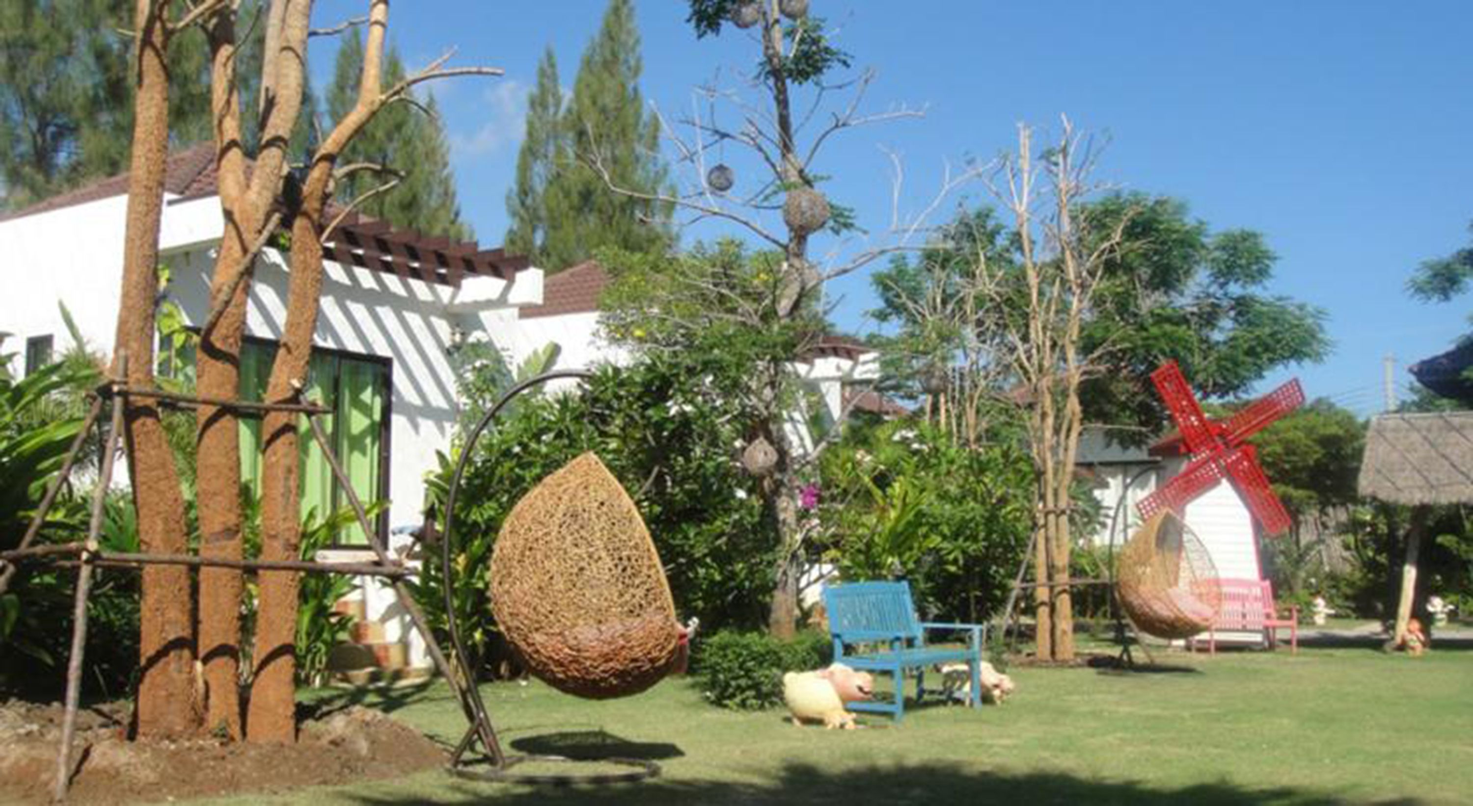 A garden with a hanging basket, a windmill, and a blue chair.