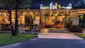 Un restaurante al aire libre con zona de estar techada, un bar y un letrero con escritura tailandesa.