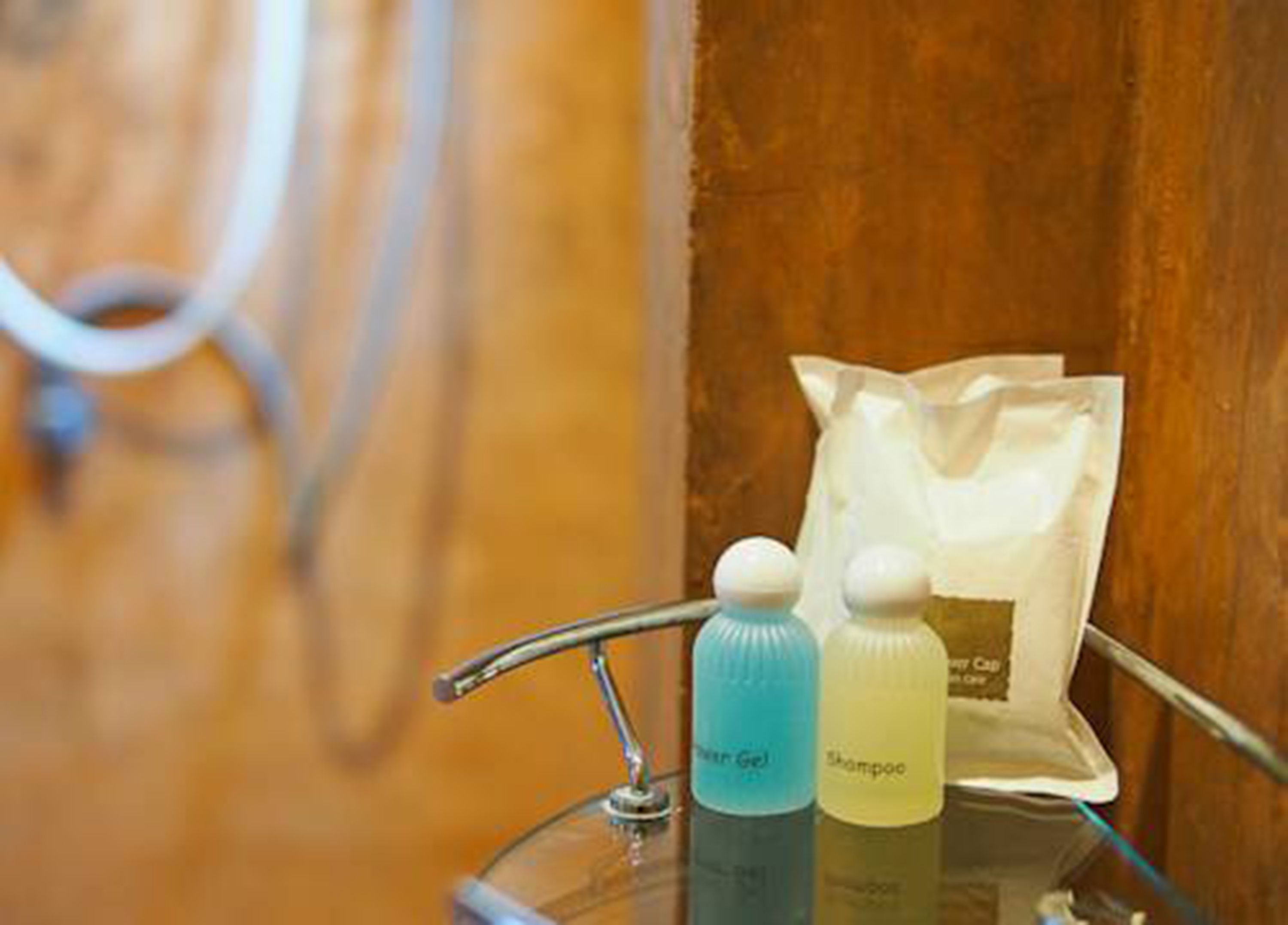 Ein Badezimmer-Waschtisch mit einem Glastaschenregal, das eine Shampooflasche, eine Spülungsflasche und eine Duschgelflasche enthält.