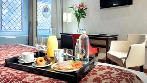Un plateau de petit-déjeuner avec des toasts, un beignet, un verre de jus d’orange, une tasse blanche et une bouteille d’eau.