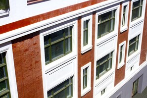 Un immeuble à plusieurs étages, doté de fenêtres à cadre blanc et de murs en briques rouges.