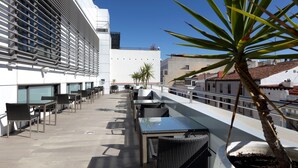Une terrasse sur le toit, avec des sièges extérieurs, un pot de fleurs et une vue sur le paysage urbain.