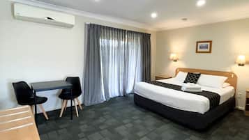 Habitación de hotel con cama, escritorio, sillas y ventana con cortinas.