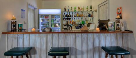 A bar area with stools, a counter, and shelves stocked with bottles.