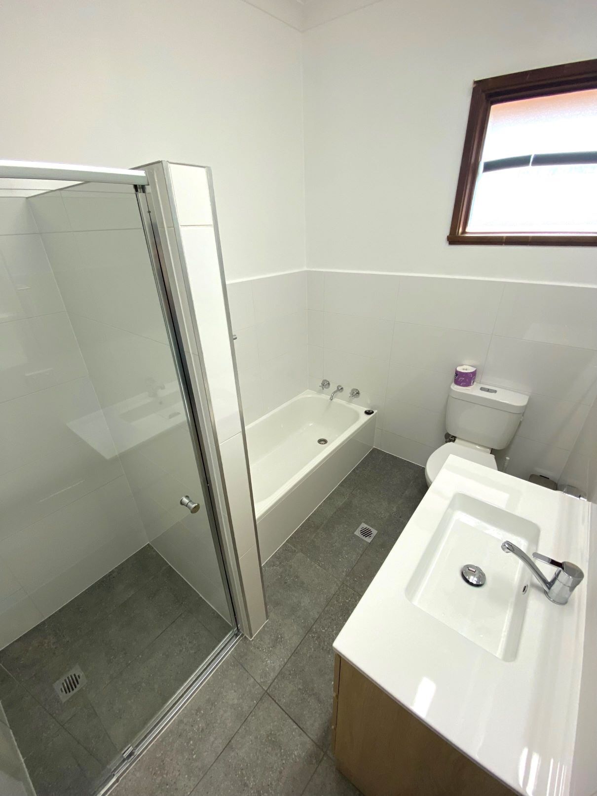 A modern bathroom with a glass shower enclosure, a bathtub, a toilet, and a sink.