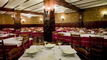 Un restaurante con varias mesas dispuestas para comer, con un fondo de pared de piedra y vigas de madera en el techo.