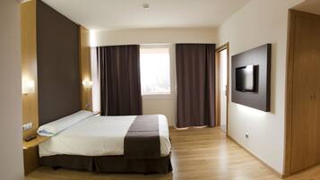 Una habitación de hotel moderna con una cama grande, un televisor de pantalla plana montado en la pared y una ventana con cortinas.
