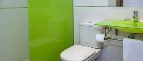 A bathroom with a white toilet, a green sink, and a white towel hanging on the wall.