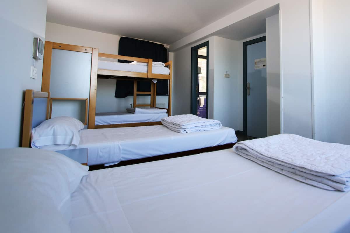 A dormitory room with bunk beds, a door, and a mirror.