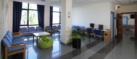 A spacious waiting area with seating, a reception desk, and a large window with curtains.