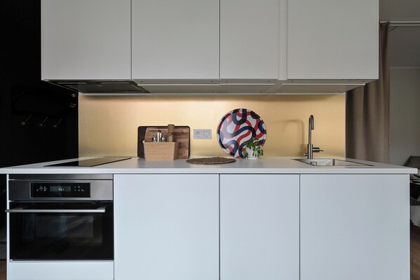 A modern kitchen with a built-in oven, a sink, and a decorative plate on the counter. - Ett Smart Sollentuna (Sollentuna)