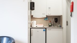 A compact kitchenette with a coffee maker, a small refrigerator, a soap dispenser, and a water bottle. - Ett Smart Sollentuna (Sollentuna)