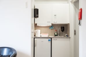 A compact kitchenette with a coffee maker, a small refrigerator, a soap dispenser, and a water bottle. - Ett Smart Sollentuna (Sollentuna)